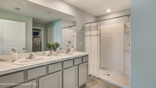 full bath featuring a shower stall, double vanity, a spacious closet, and tile patterned flooring