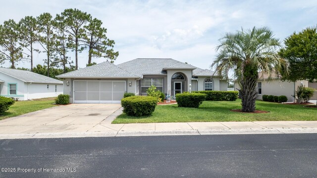 ranch-style home with an attached garage, concrete driveway, a front lawn, and stucco siding