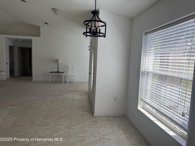 unfurnished dining area featuring plenty of natural light, vaulted ceiling, a chandelier, and baseboards