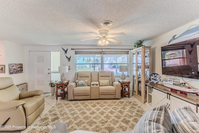 living room with light tile patterned floors, ceiling fan, and a textured ceiling