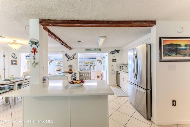 kitchen featuring stainless steel appliances, white cabinetry, light countertops, light tile patterned flooring, and a textured ceiling