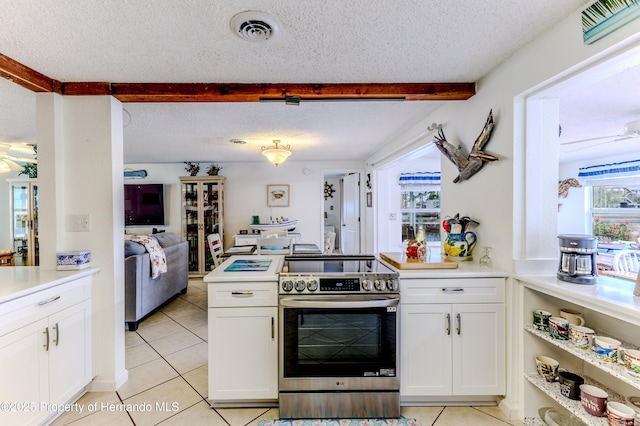 kitchen featuring stainless steel electric range, light tile patterned flooring, white cabinetry, a textured ceiling, and light countertops