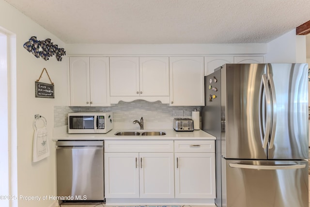 kitchen with stainless steel appliances, a sink, white cabinetry, and tasteful backsplash