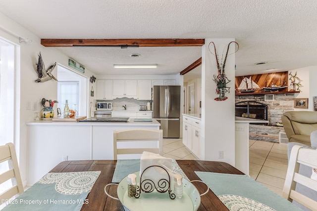 kitchen with stainless steel appliances, open floor plan, light tile patterned floors, a fireplace, and a textured ceiling