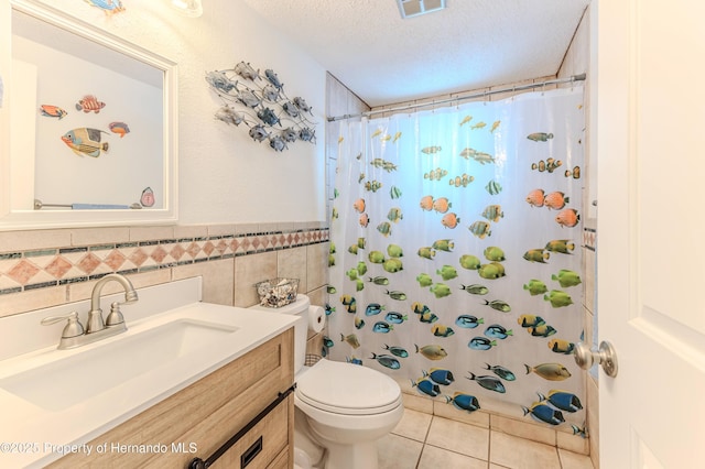 full bath featuring tile patterned flooring, a textured ceiling, toilet, a shower with shower curtain, and tile walls