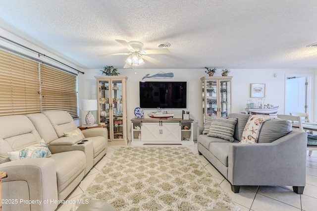 living area with a ceiling fan, light tile patterned flooring, and a textured ceiling