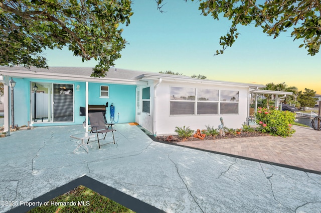back of property at dusk featuring a patio area and stucco siding
