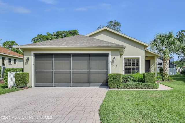 ranch-style home featuring stucco siding, decorative driveway, a front lawn, and a garage