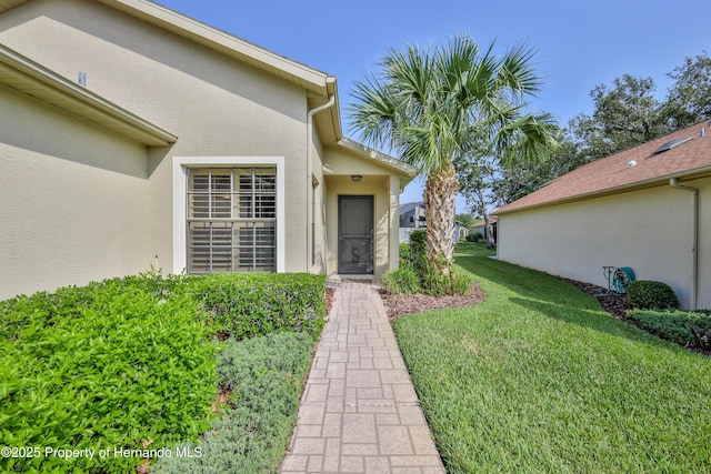 doorway to property with stucco siding and a lawn