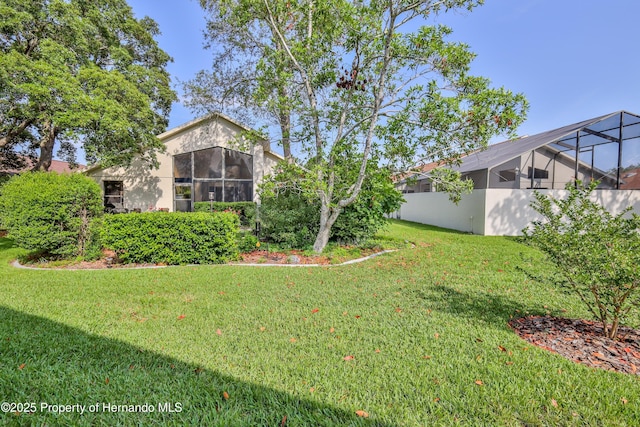 view of grassy yard with a lanai