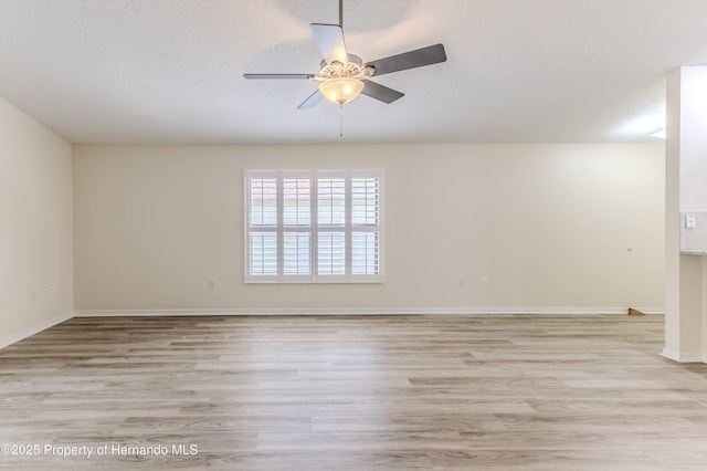 unfurnished room with light wood-style flooring, a ceiling fan, baseboards, and a textured ceiling
