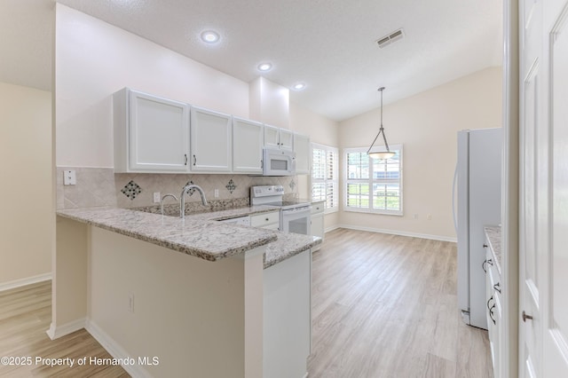 kitchen with white appliances, light wood-type flooring, a peninsula, decorative backsplash, and light stone countertops