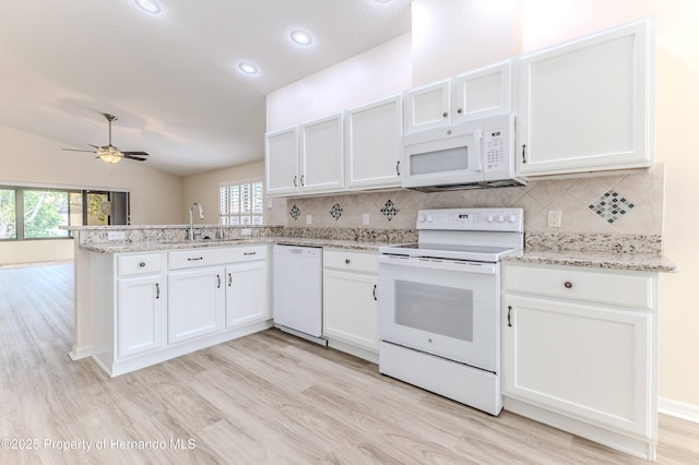 kitchen featuring white appliances, a sink, a peninsula, light wood-style floors, and white cabinetry