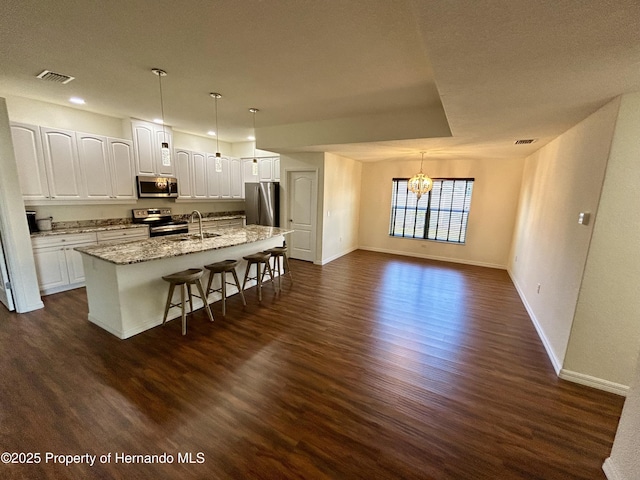 15585 Rene Ct, Brooksville, FL 34604 - kitchen with appliances with stainless steel finishes, baseboards, dark wood-style floors, a kitchen breakfast bar, and a chandelier