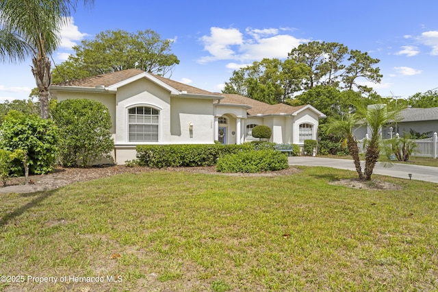 mediterranean / spanish home with stucco siding, driveway, and a front lawn