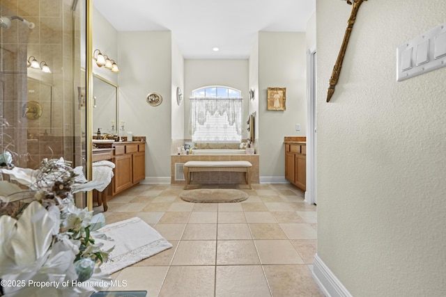 bathroom featuring a stall shower, vanity, a garden tub, tile patterned floors, and baseboards