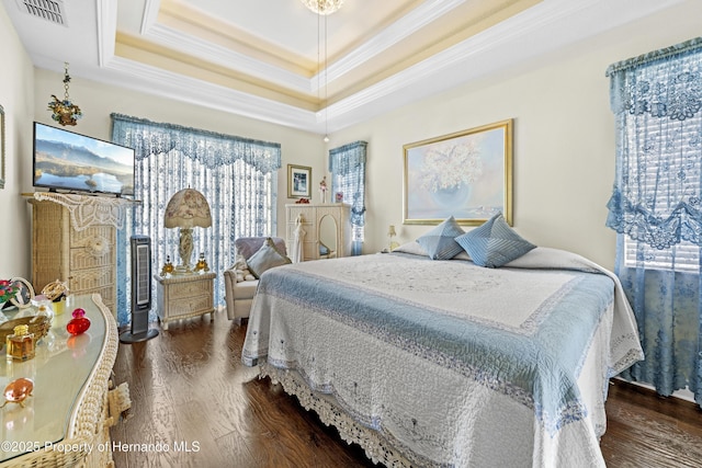 bedroom with multiple windows, dark wood-style flooring, ornamental molding, and a tray ceiling