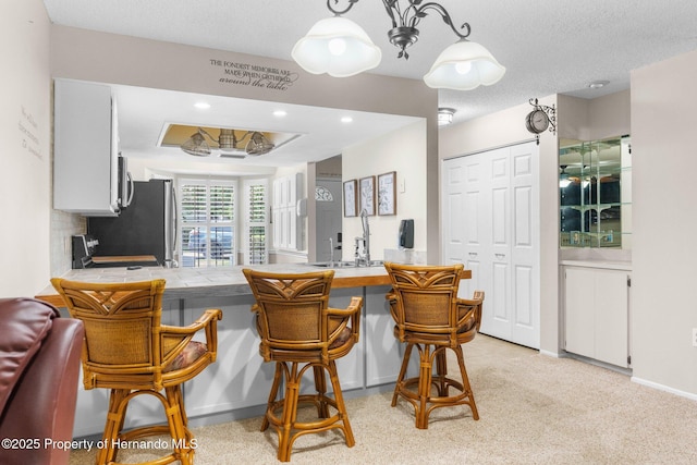 dining area with light carpet, bar with sink, and recessed lighting