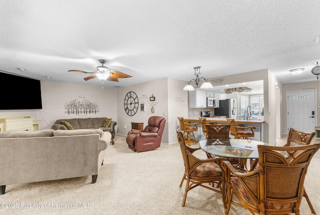 dining space with light carpet, a ceiling fan, a chandelier, a textured ceiling, and baseboards