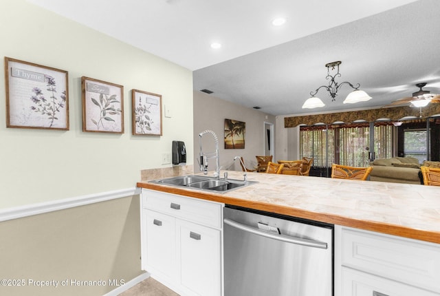 kitchen with dishwasher, a sink, white cabinetry, open floor plan, and hanging light fixtures