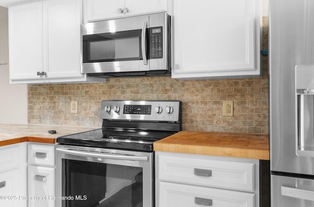kitchen featuring appliances with stainless steel finishes, butcher block countertops, white cabinetry, and backsplash