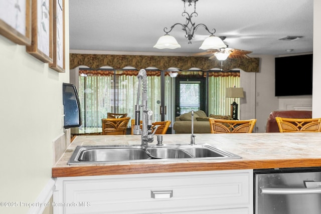 kitchen with a sink, open floor plan, ceiling fan, and white cabinetry