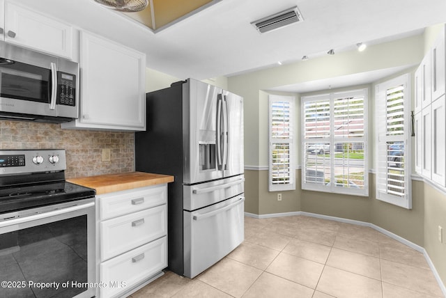 kitchen featuring stainless steel appliances, backsplash, baseboards, and white cabinetry