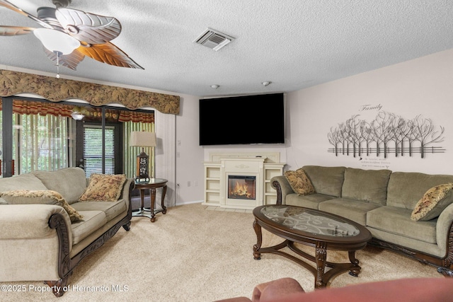 carpeted living area featuring a textured ceiling, a fireplace with flush hearth, and ceiling fan
