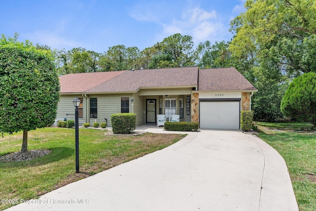 single story home featuring covered porch, an attached garage, a front yard, concrete driveway, and roof with shingles