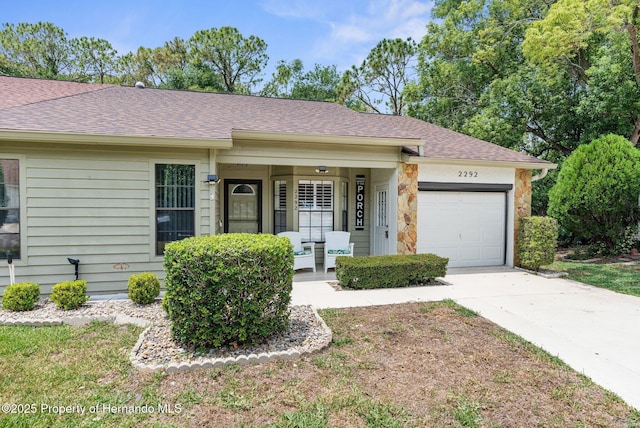 ranch-style house featuring a porch, an attached garage, driveway, and roof with shingles
