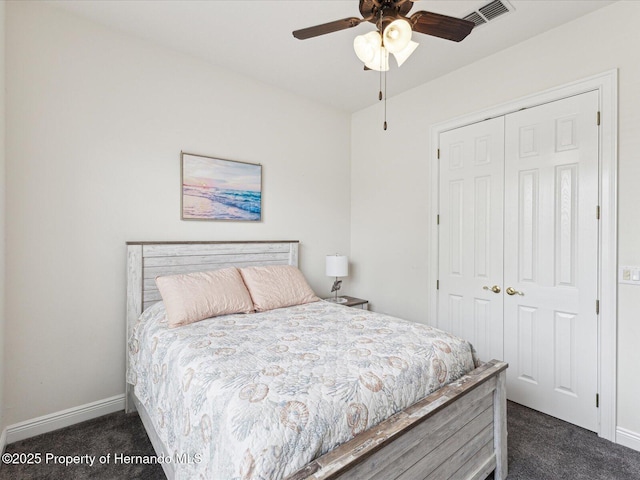 bedroom with dark colored carpet, a closet, and baseboards
