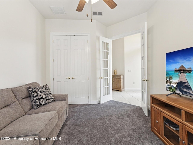 carpeted living room with french doors, a ceiling fan, and tile patterned floors