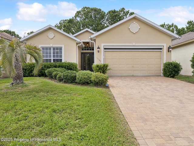 view of front of house with decorative driveway, a garage, a front lawn, and stucco siding