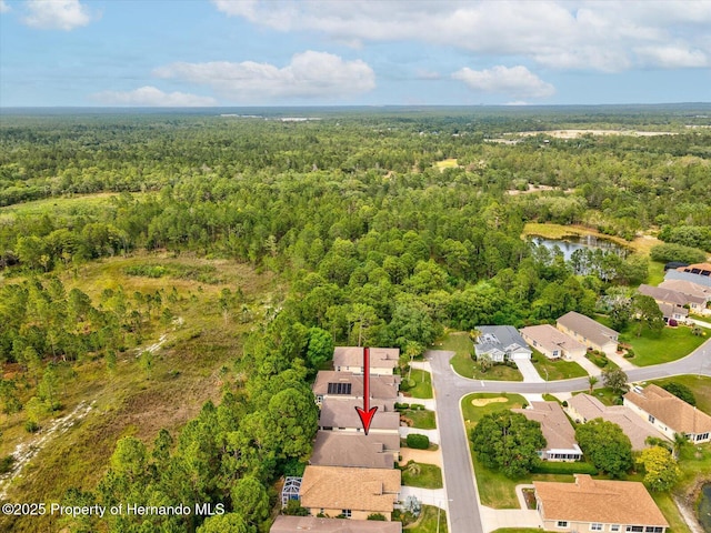 aerial view of property and surrounding area with a heavily wooded area and nearby suburban area