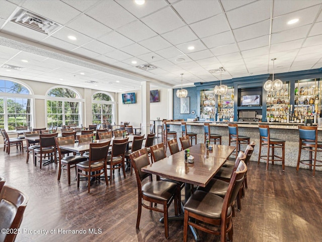 dining room with a drop ceiling, wood-type flooring, healthy amount of natural light, and a chandelier