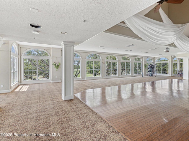 unfurnished living room with baseboards, decorative columns, and a ceiling fan