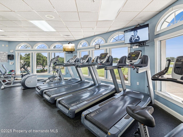 exercise room with a paneled ceiling, plenty of natural light, and baseboards