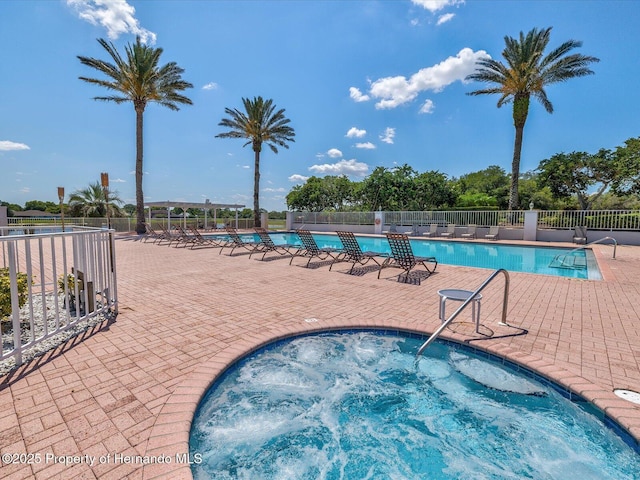 community pool featuring fence, a patio area, and a hot tub