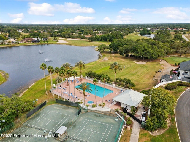 drone / aerial view of a large body of water, a pool area, a tree filled landscape, and a local golf course