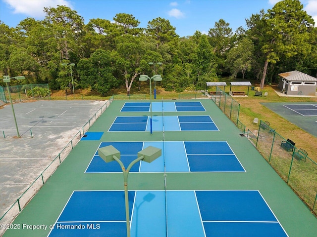 view of property's community featuring a tennis court and fence