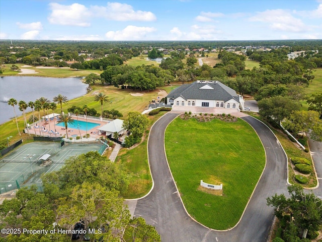 drone / aerial view of a large body of water, a tree filled landscape, and a pool area