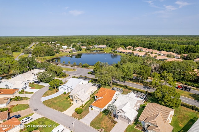 aerial perspective of suburban area featuring a nearby body of water and a heavily wooded area
