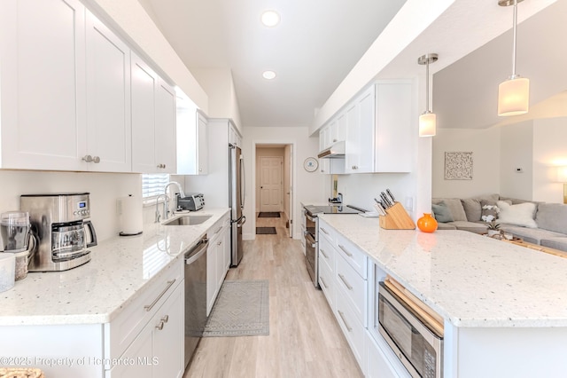 kitchen with appliances with stainless steel finishes, a sink, light wood-style flooring, open floor plan, and white cabinetry
