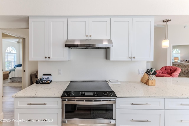 kitchen with stainless steel range with electric stovetop, under cabinet range hood, white cabinetry, light stone counters, and pendant lighting