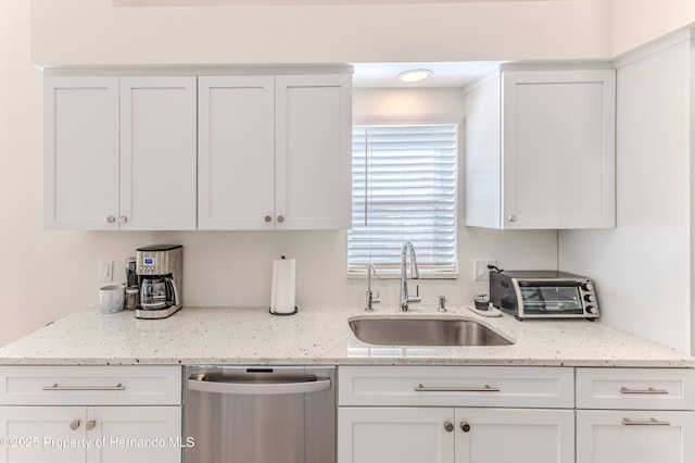 kitchen featuring dishwasher, a sink, white cabinetry, and light stone counters