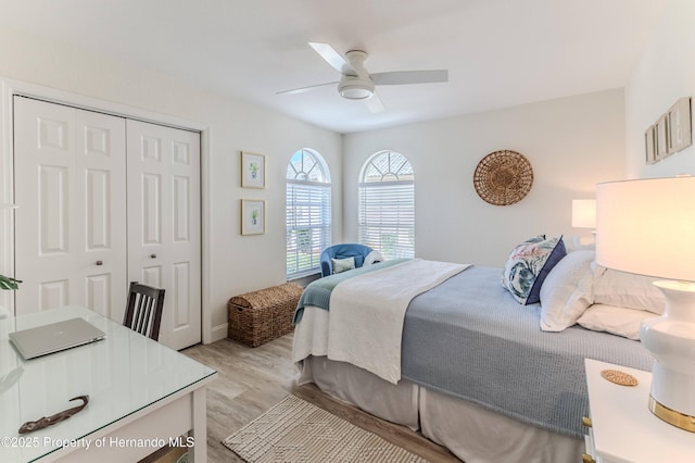 bedroom with light wood-style floors, a closet, ceiling fan, and baseboards