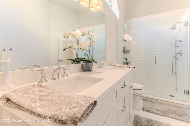 bathroom with toilet, a shower stall, and double vanity