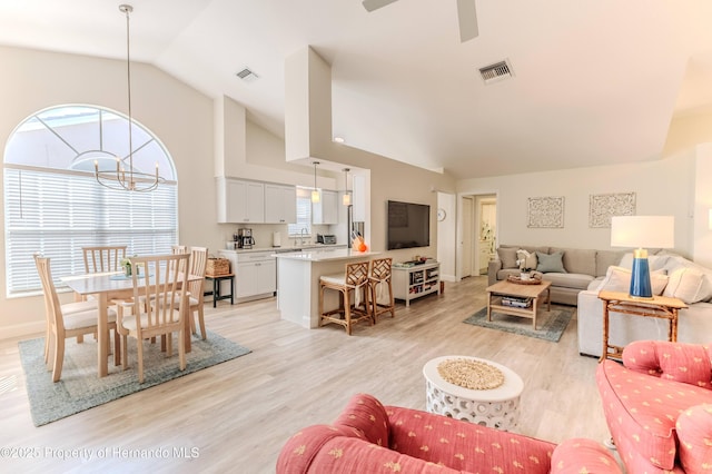 living room with lofted ceiling, light wood-type flooring, ceiling fan, baseboards, and a chandelier