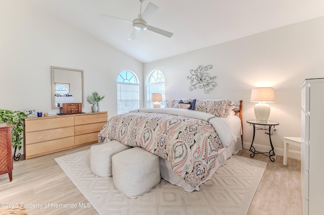 bedroom with light wood finished floors, vaulted ceiling, baseboards, and ceiling fan