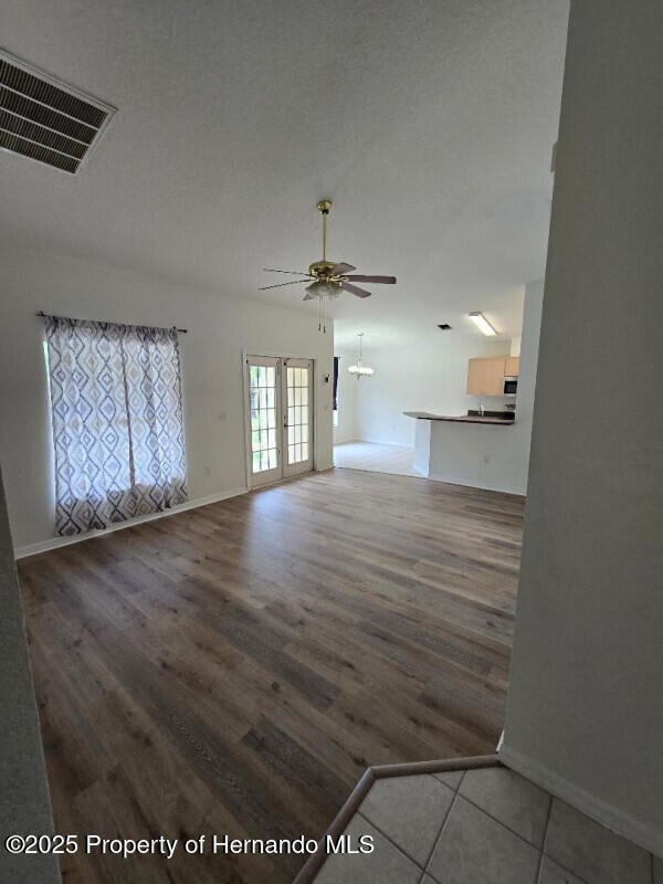 unfurnished living room featuring ceiling fan, wood finished floors, and baseboards